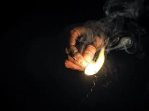 Hand holding a lit match illustrating the risk of serious burn injuries