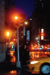 City intersection at night with glowing traffic lights and wet streets