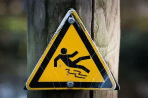 Yellow slip and fall warning sign mounted on a wooden pole outdoors