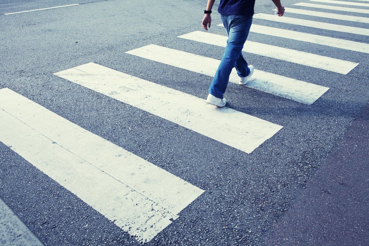 Man in jeans walking across a zebra crossing Pedestrian crossing a crosswalk at an Illinois intersection